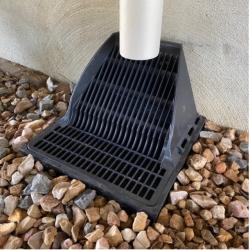 installed downspout defender over bed of rocks